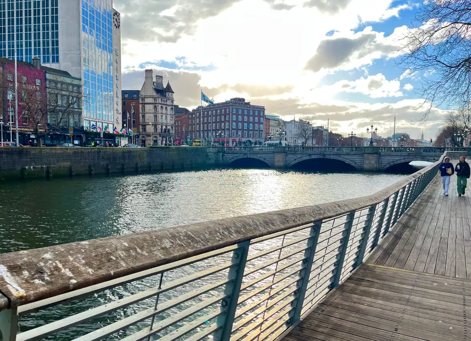 El río Liffey y su paseo peatonal en el centro de Dublín, con edificios modernos al fondo