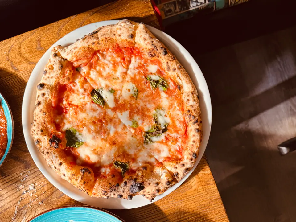 Pizza margherita recién horneada, con mozzarella, tomate y albahaca, en Nápoles